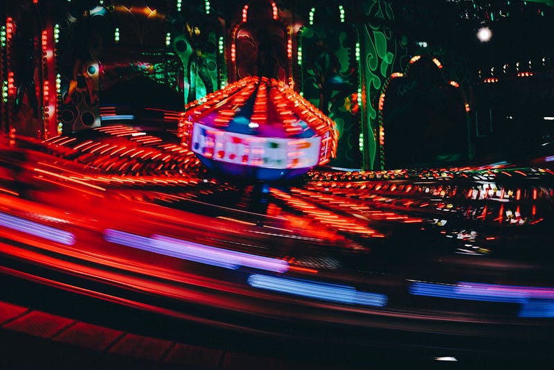 The blurred red lights of a carnival ride, moving through the dark.