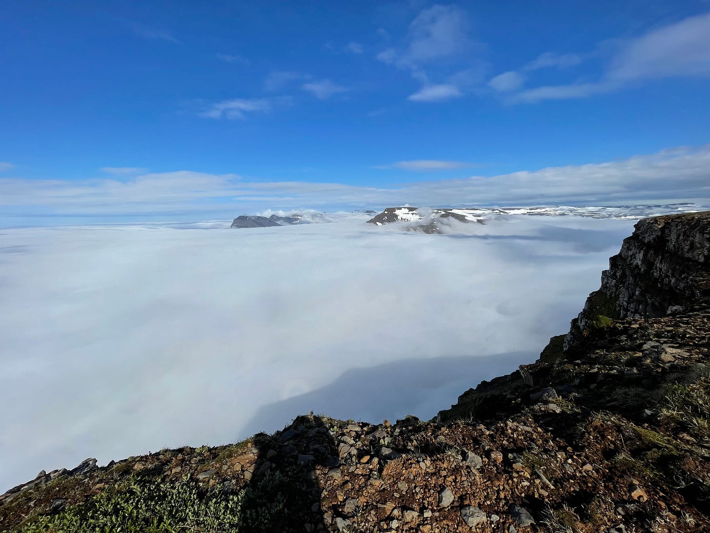 Standing at the edge of a cliff, overlooking a dense fog that conceals the entire sea and stretches to the horizon Standing at the edge of a cliff, overlooking a dense fog that conceals the entire sea and stretches to the horizon