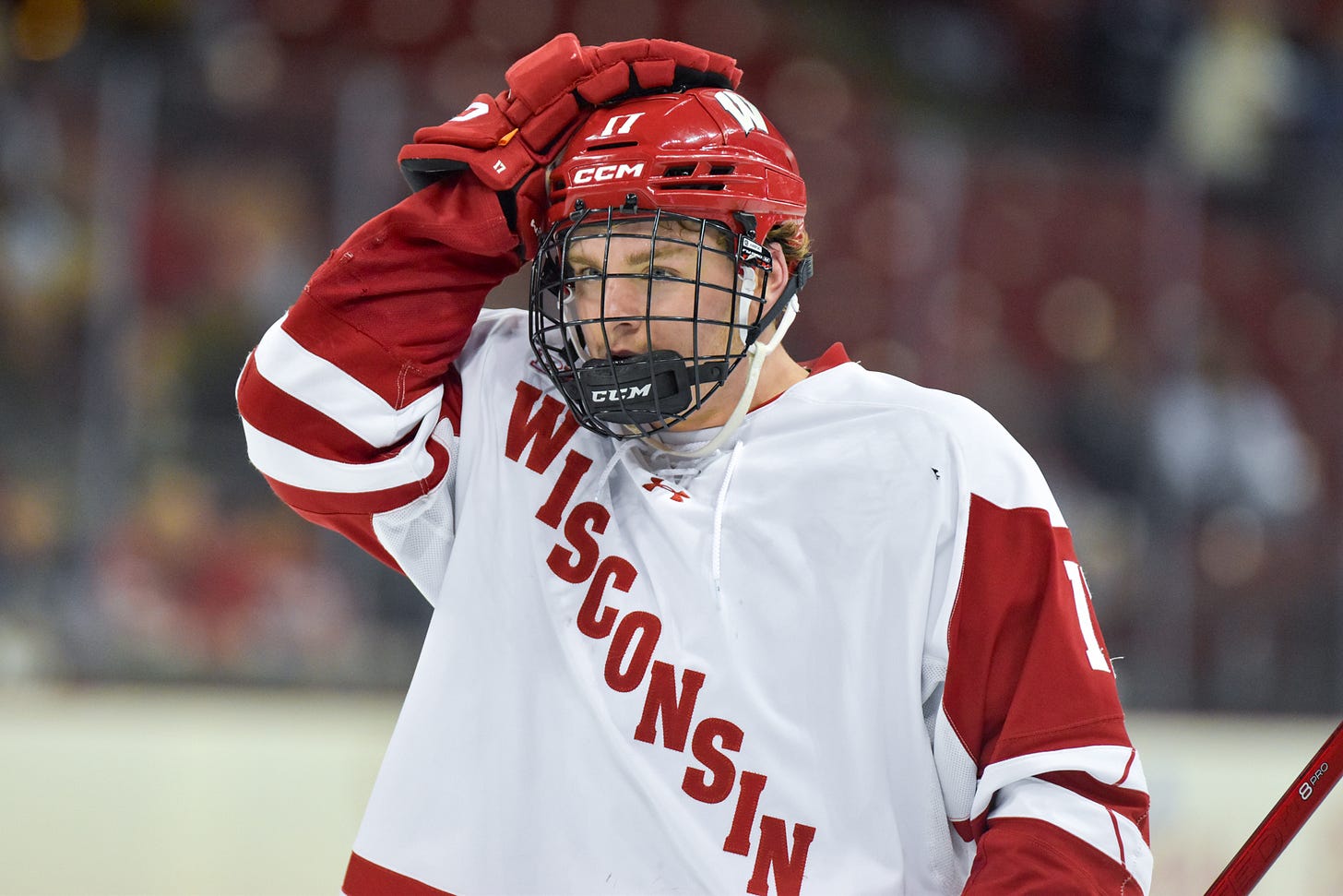 wisconsin men's hockey player grady deering puts his hand on his helmet