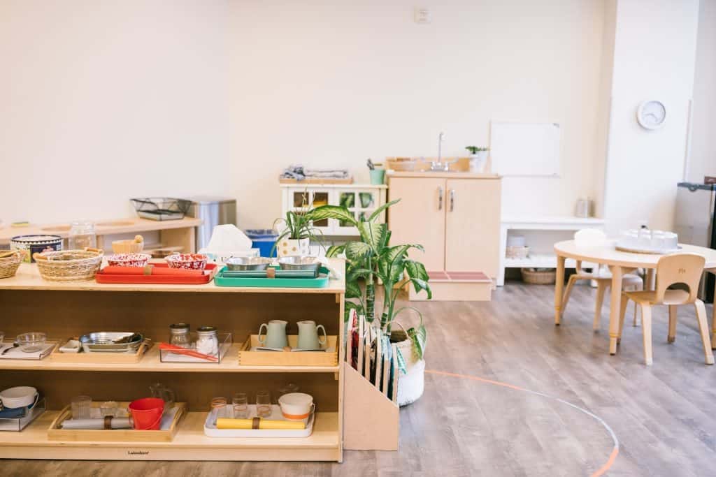 Montessori practical life shelf with trays, pitchers, and natural materials — what is Montessori prepared environment