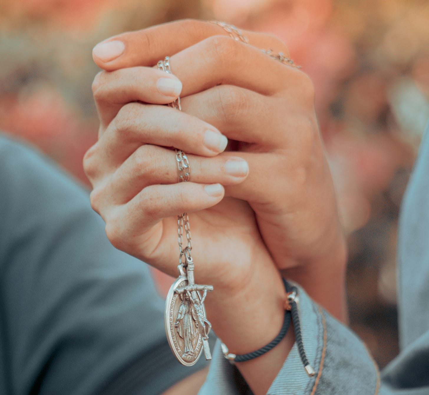 Couple hands with crucifix and miraculous medal