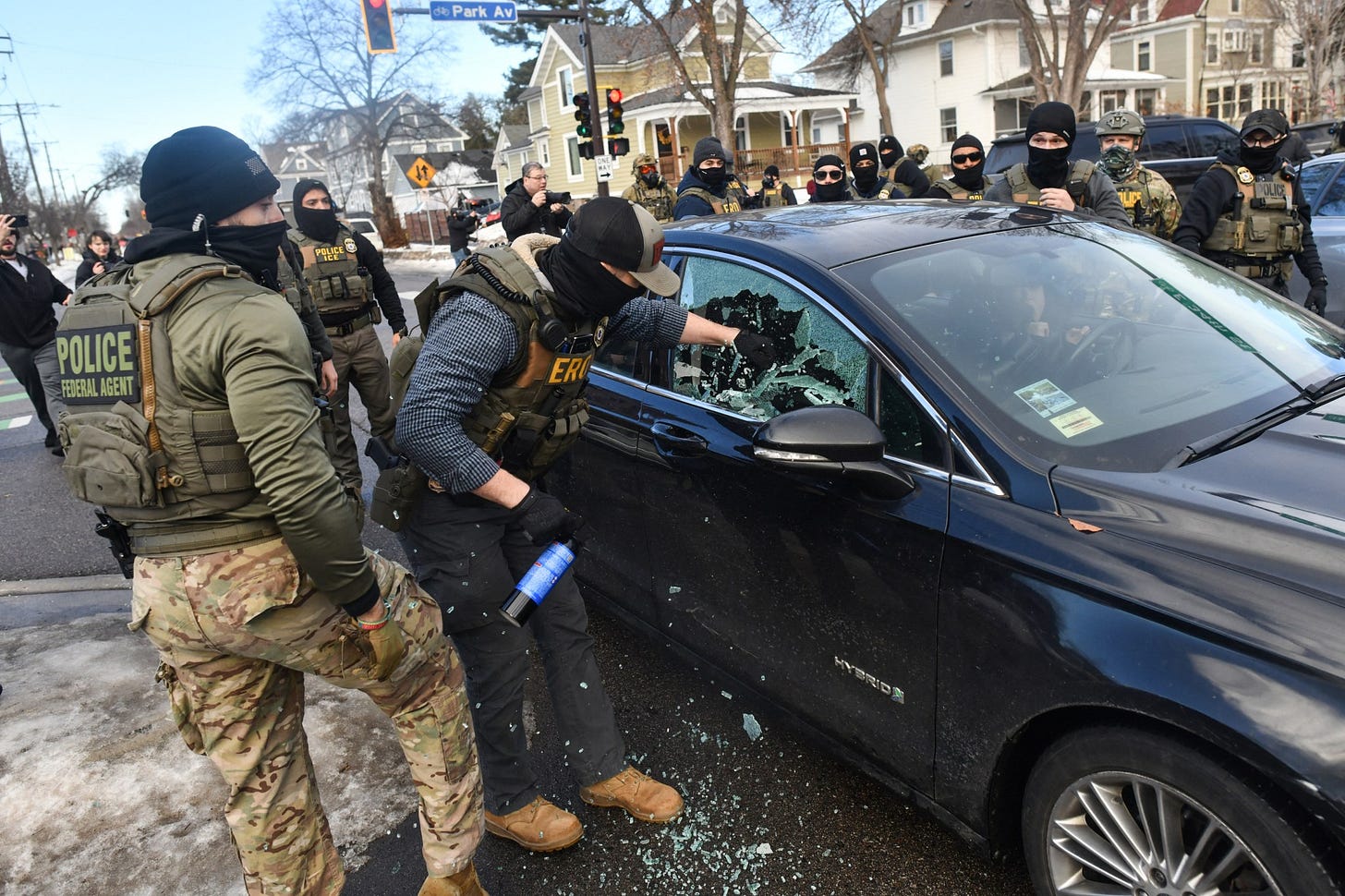 ICE and other federal officers break a car window as they begin the process of removing a woman from her vehicle near an area where ICE was operating in Minneapolis, Minnesota, on January 13, 2026.