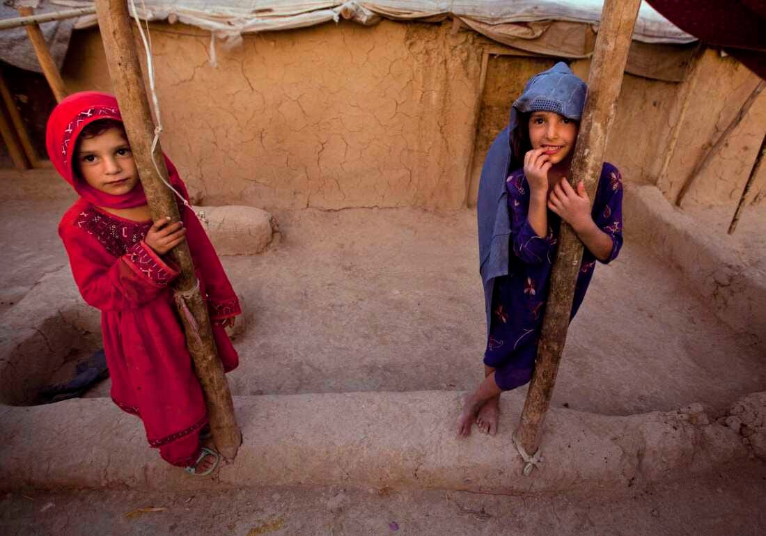 FILE: Zareena, left, and Shakeela, internally displaced Afghan girls play outside a shanty at a refugee camp in the outskirts of Kabul, Afghanistan, Monday, July 25, 2011.