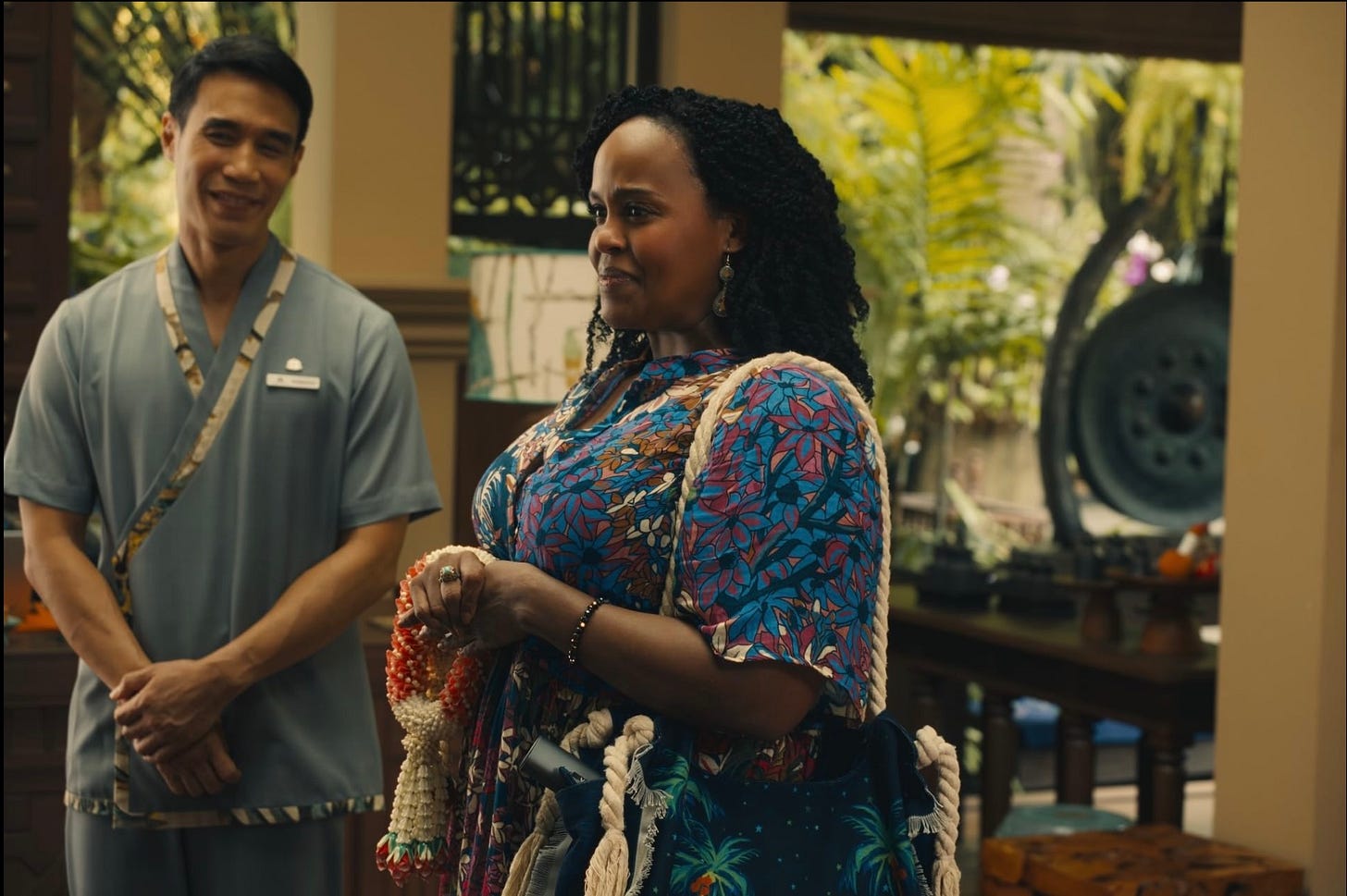 A man in a blue shirt and a woman to his right in a floral dress, they're both smiling