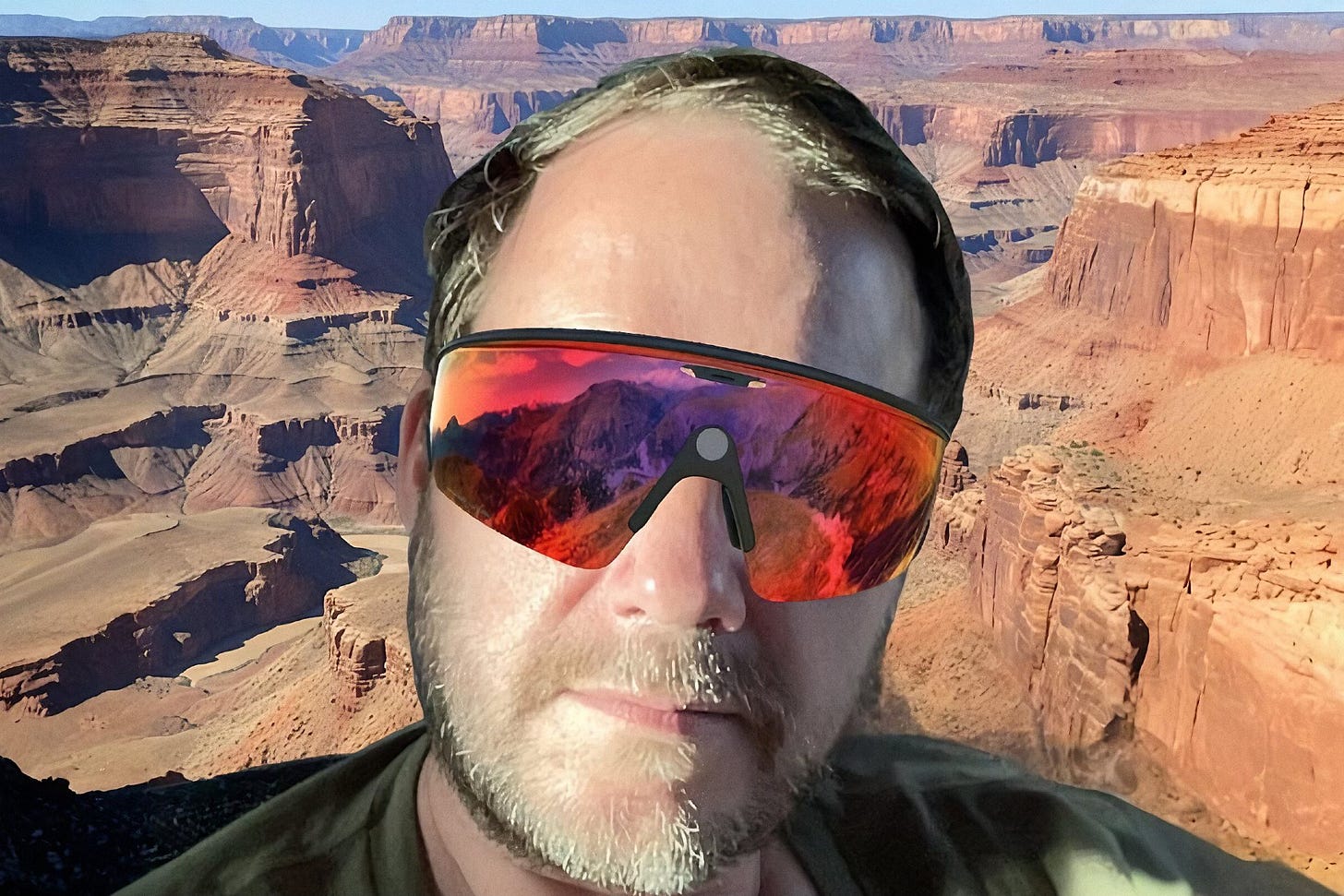 A devastatingly handsome middle-aged man (me!) wearing a pair of Meta Oakley smart glasses with pink lenses, in a desert canyon.