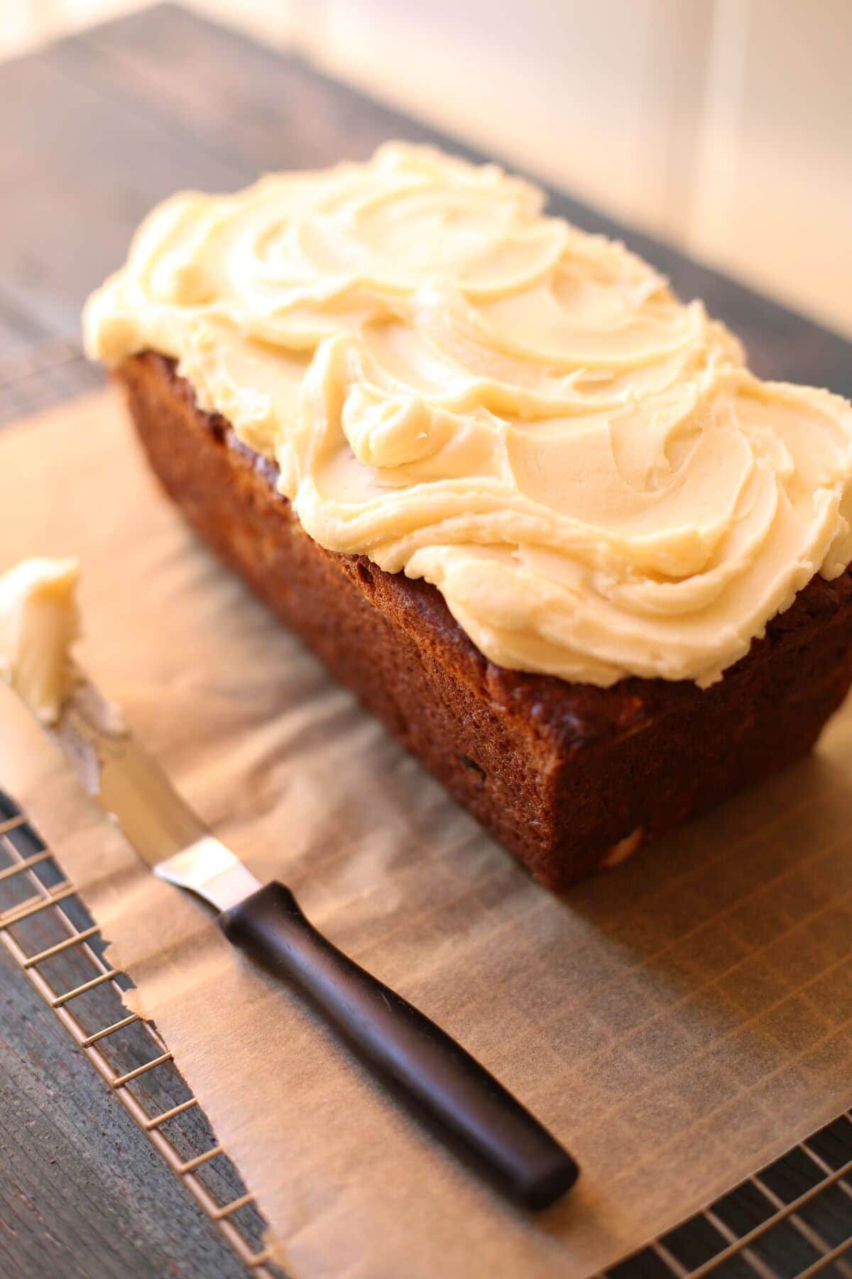 Banana bread on a table with frosting knife
