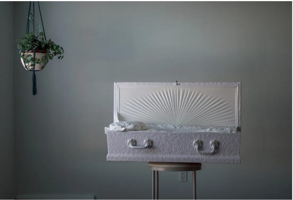 Image displays a small white open coffin