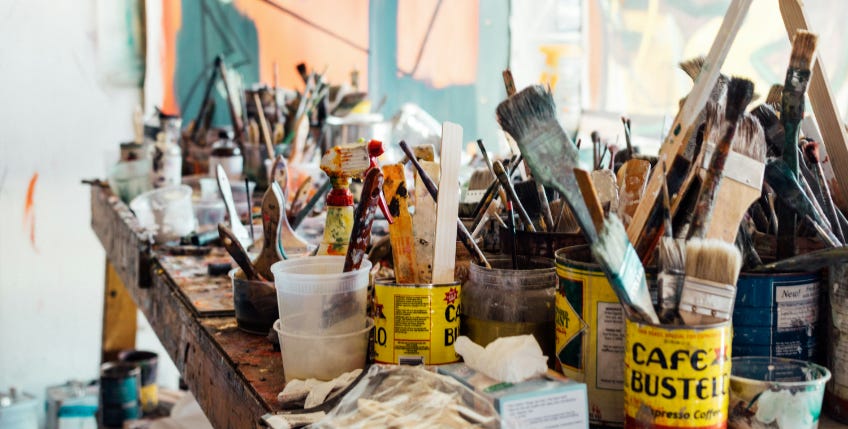 Artist's studio table covered in brushes, paints and pots