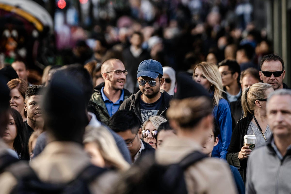 a photo of a crowded sidewalk where some people are in focus while others are not a photo of a crowded sidewalk where some people are in focus while others are not