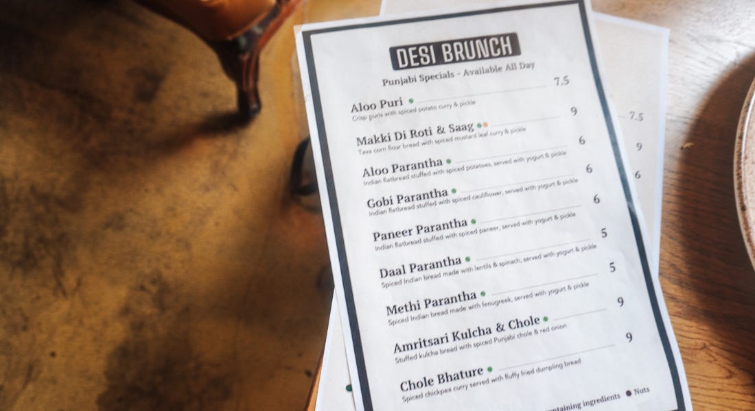 A table with a white menu with writing on it that says 'Desi brunch'
