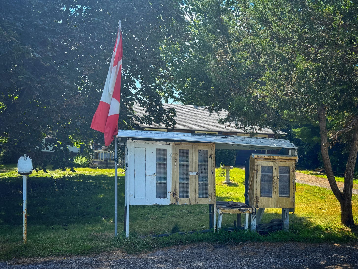 The former Rouge Park Pie Stand. A series of wooden cabinets with glass front doors, covered by a small roof. They once held pies and tarts that could be bought on the honour system. They are now empty. A Canadian flag on a flag pole is immediately to the left. A rural mailbox is at the left side of the image. The former Rouge Park Pie Stand. A series of wooden cabinets with glass front doors, covered by a small roof. They once held pies and tarts that could be bought on the honour system. They are now empty. A Canadian flag on a flag pole is immediately to the left. A rural mailbox is at the left side of the image.