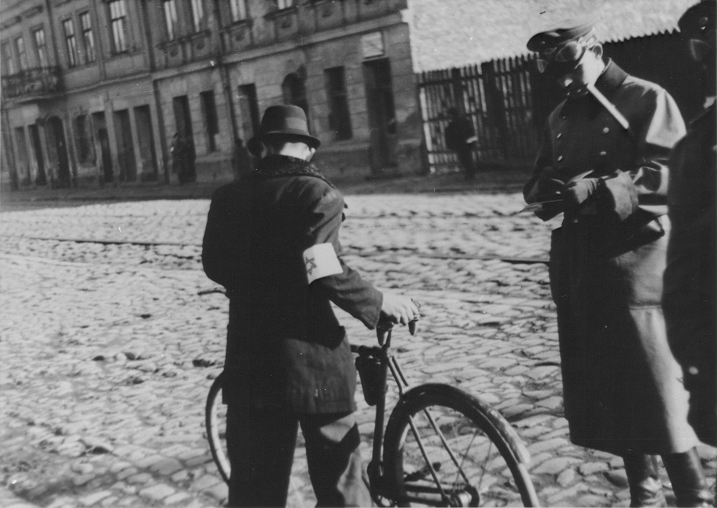 A German policeman checks the papers of a Jewish cyclist on a street in the Warsaw ghetto. A German policeman checks the papers of a Jewish cyclist on a street in the Warsaw ghetto.