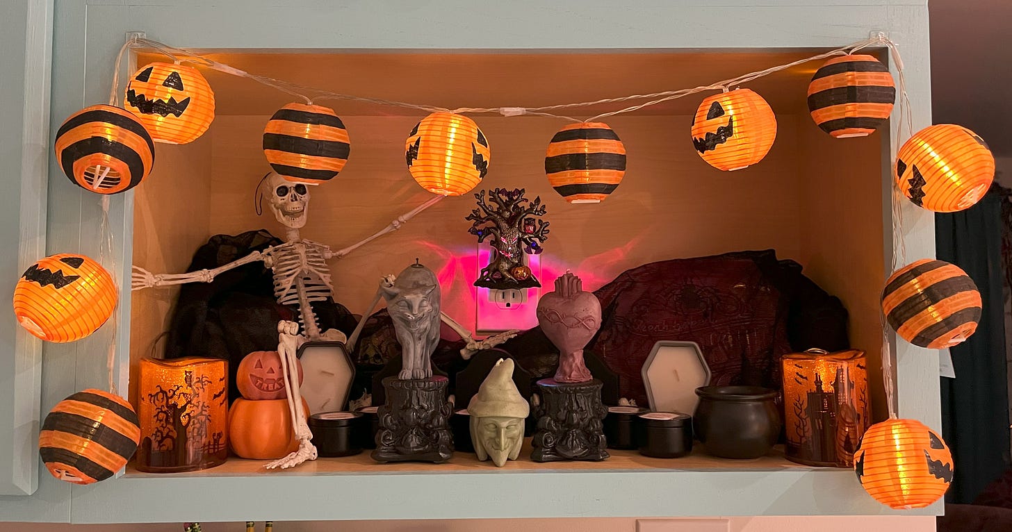 A toy skeleton sitting amongst a display of various Halloween decorations.