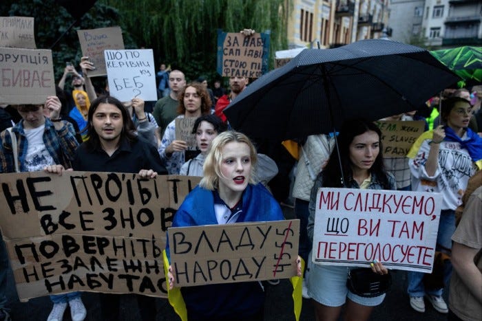 Protesters hold handwritten signs and shout during a demonstration in July calling for independent anti-corruption agencies in Kyiv.