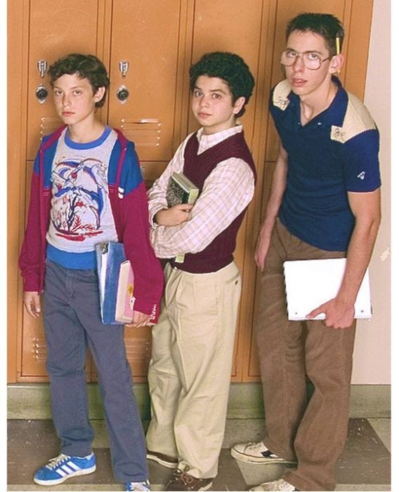 This may contain: three young boys standing in front of lockers