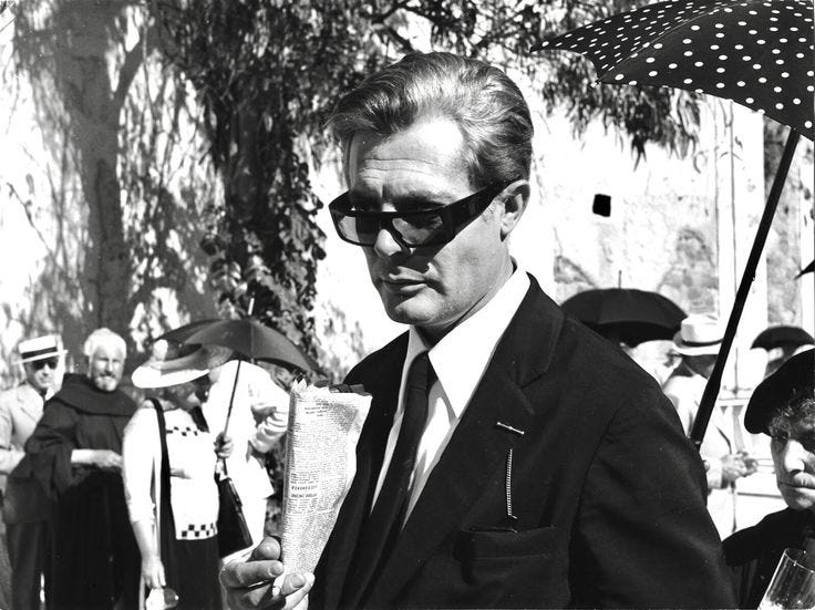 This may contain: black and white photograph of man in suit holding an umbrella while people watch from behind him This may contain: black and white photograph of man in suit holding an umbrella while people watch from behind him