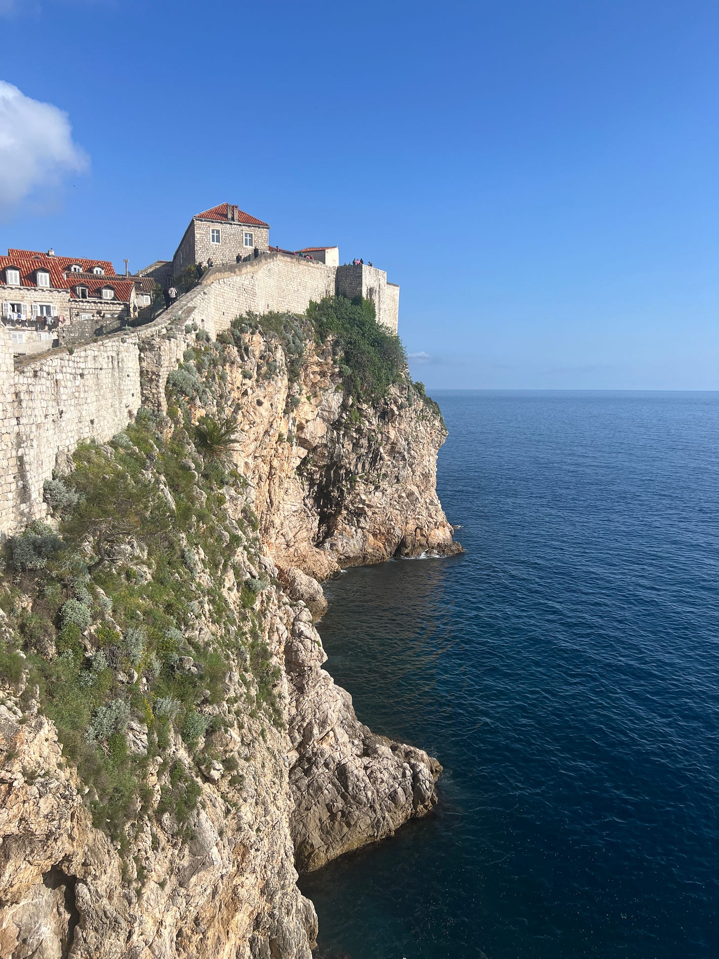 Cliff in Dubrovnik with city walls perched on it.