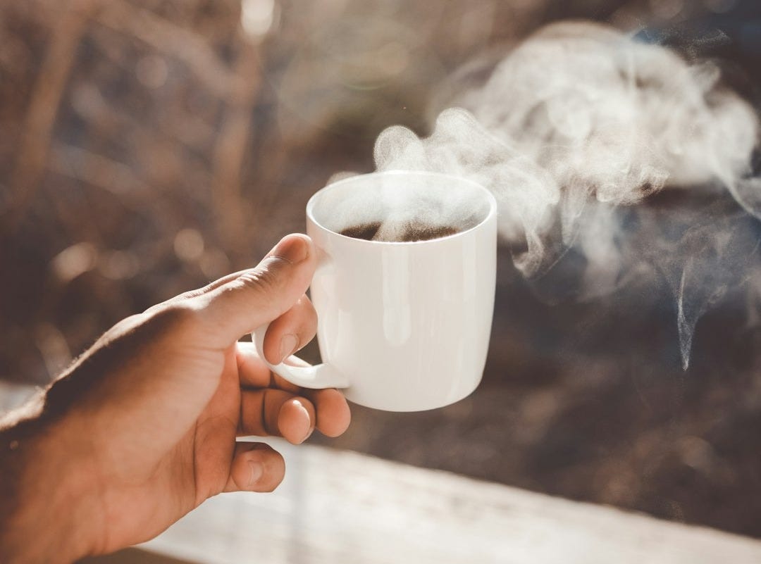 person holding white ceramic cup with hot coffee person holding white ceramic cup with hot coffee