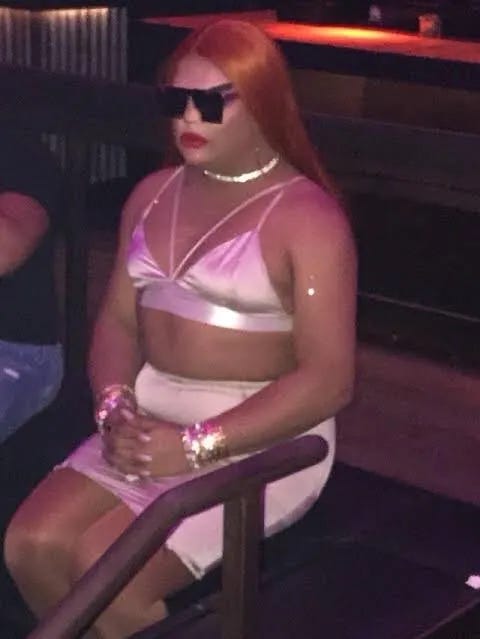 Kandi Muse sitting alone in a club wearing a pink outfit and sunglasses Kandi Muse sitting alone in a club wearing a pink outfit and sunglasses