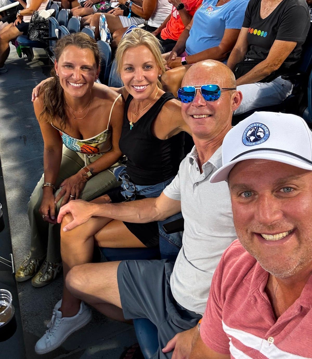 Friends enjoying courtside seats at Cincinnati Open ATP Masters 1000 tournament, smiling group of tennis spectators in blue stadium seating during professional tennis match