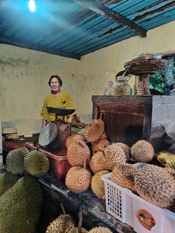 On the right are a group of women at the Pura Tirtha Empul in Bali, Indonesia. On the left, a durian seller stands with durians and a weighing scale inside her hut. Photos: Mahima Jain