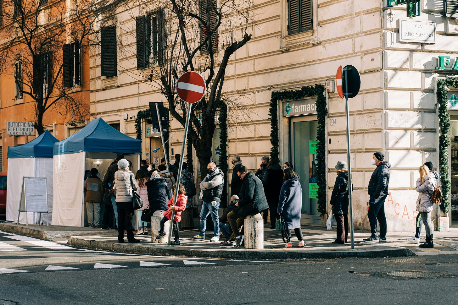 Line snaking around an Italian pharmacy in winter