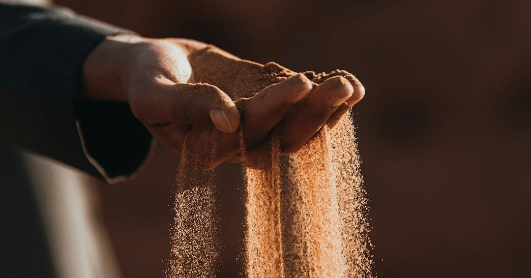 a person holding sand in their hands