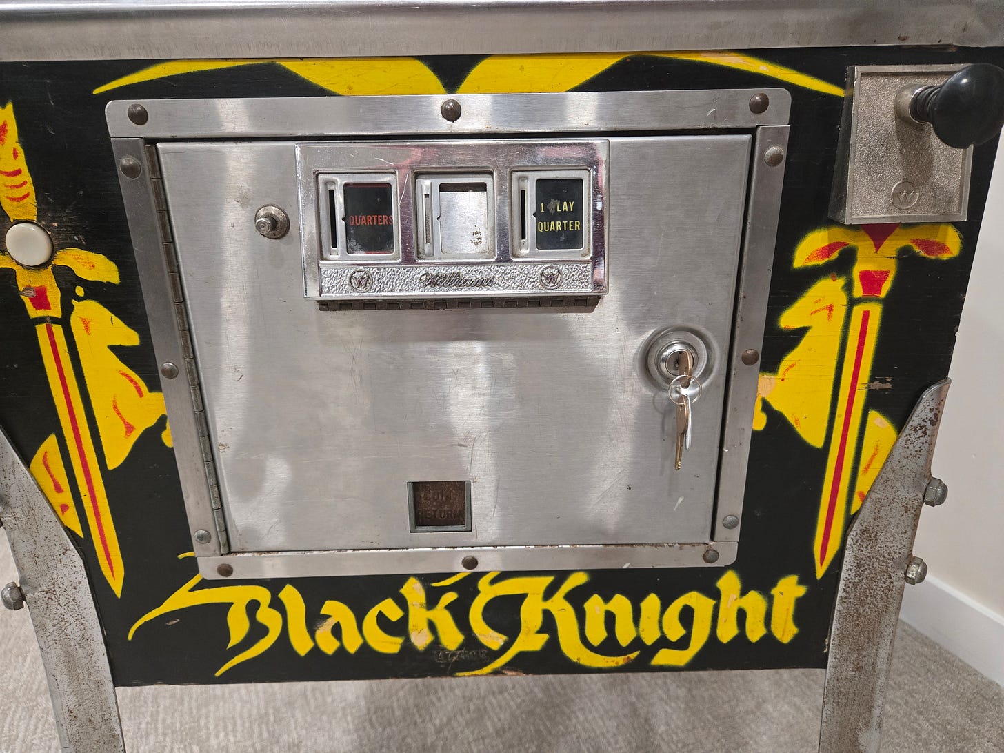 Black Knight (1980) cabinet front door showing the coin mechanism and 'Black Knight' name lettering, illustrating the front-door diagnostic access feature Black Knight (1980) cabinet front door showing the coin mechanism and 'Black Knight' name lettering, illustrating the front-door diagnostic access feature