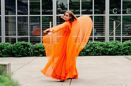 A redhead twirls in an orange dress.