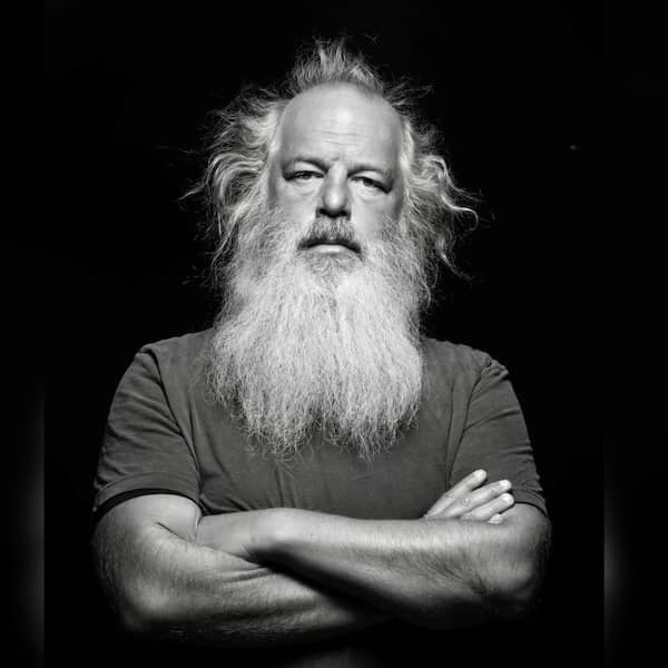 A black and white portrait of a man with long, wild hair and a full beard, crossing his arms and staring directly at the camera with a serious expression. A black and white portrait of a man with long, wild hair and a full beard, crossing his arms and staring directly at the camera with a serious expression.