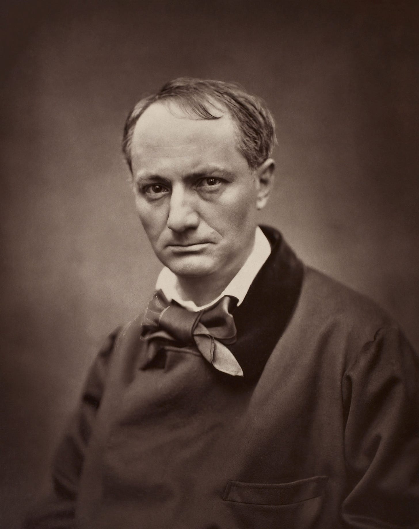A picture of a man in black clothing with a full silk bowtie in a white collar. 