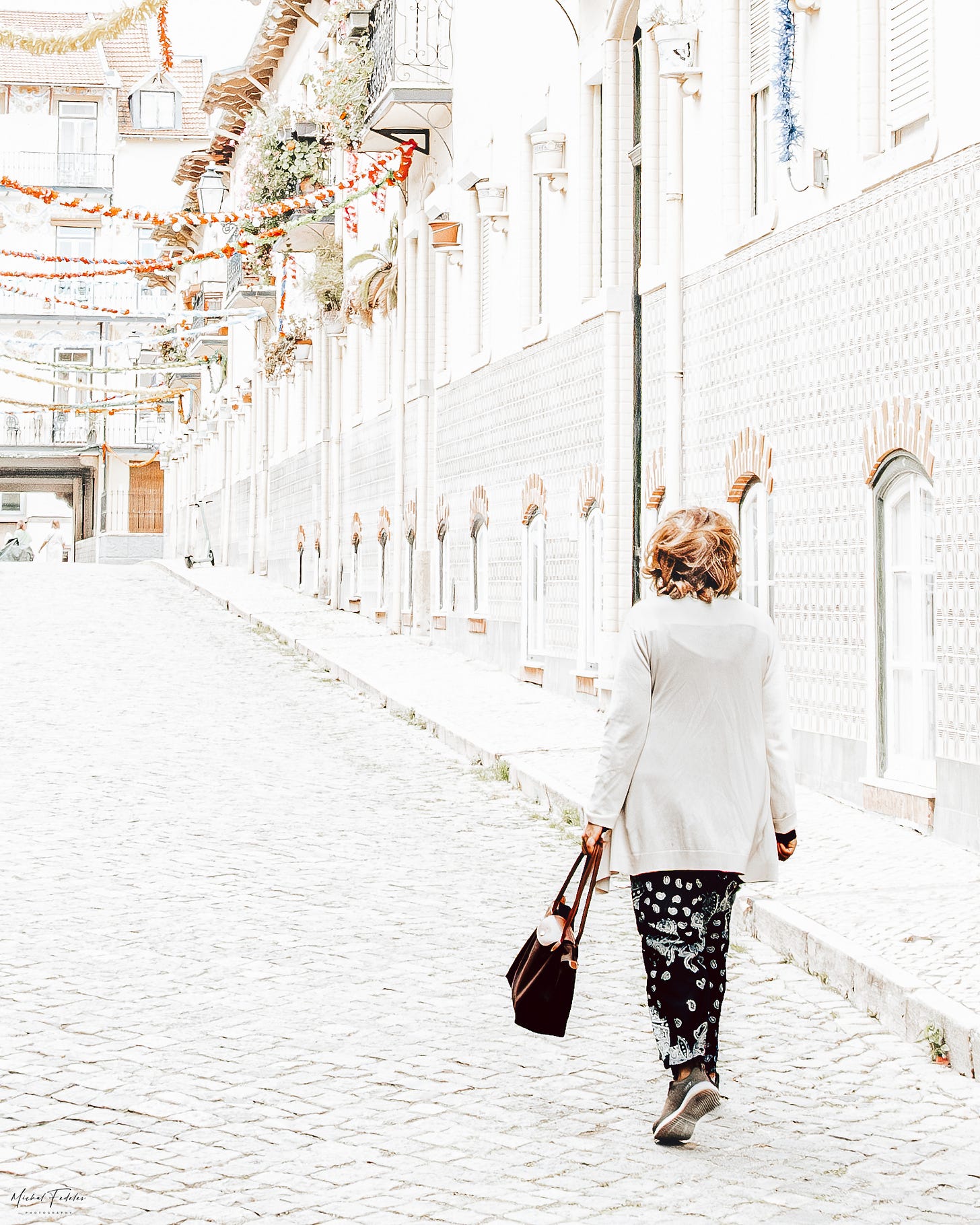 A woman in white walks along a car-free street