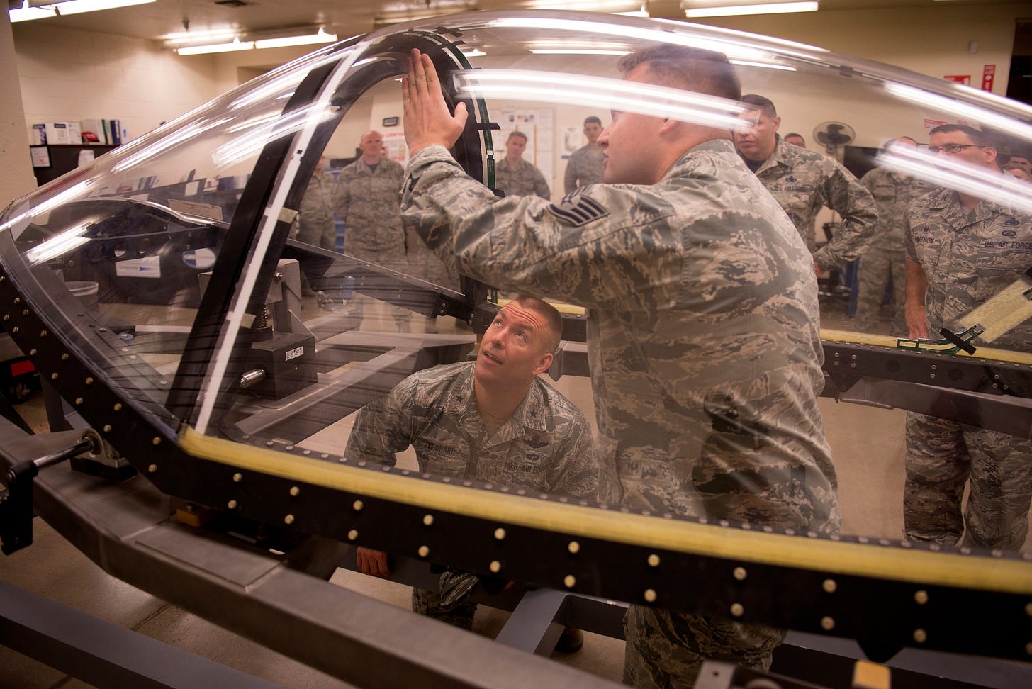 US Air Force personnel examining an F-35 canopy component during maintenance at Luke Air Force Base.