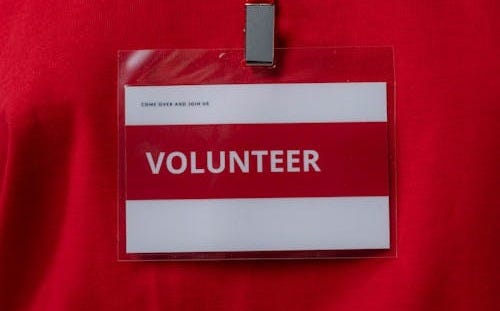Free A close-up of a volunteer name tag hanging on a red lanyard, symbolizing community service. Stock Photo