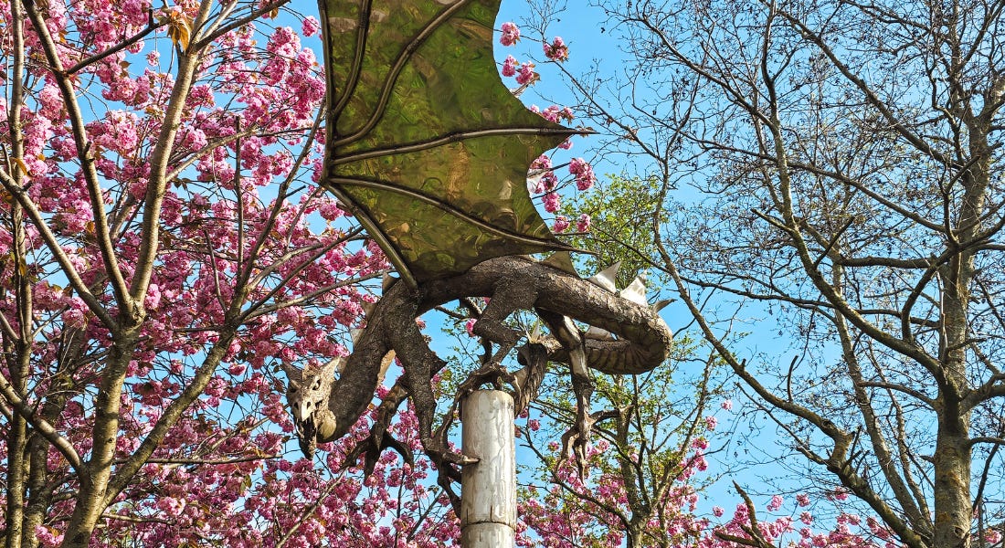 A dragon statue with blossom trees around it A dragon statue with blossom trees around it