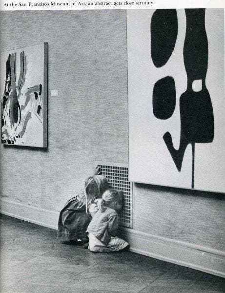 This may contain: two children are sitting on the floor in front of some paintings and one is holding his head