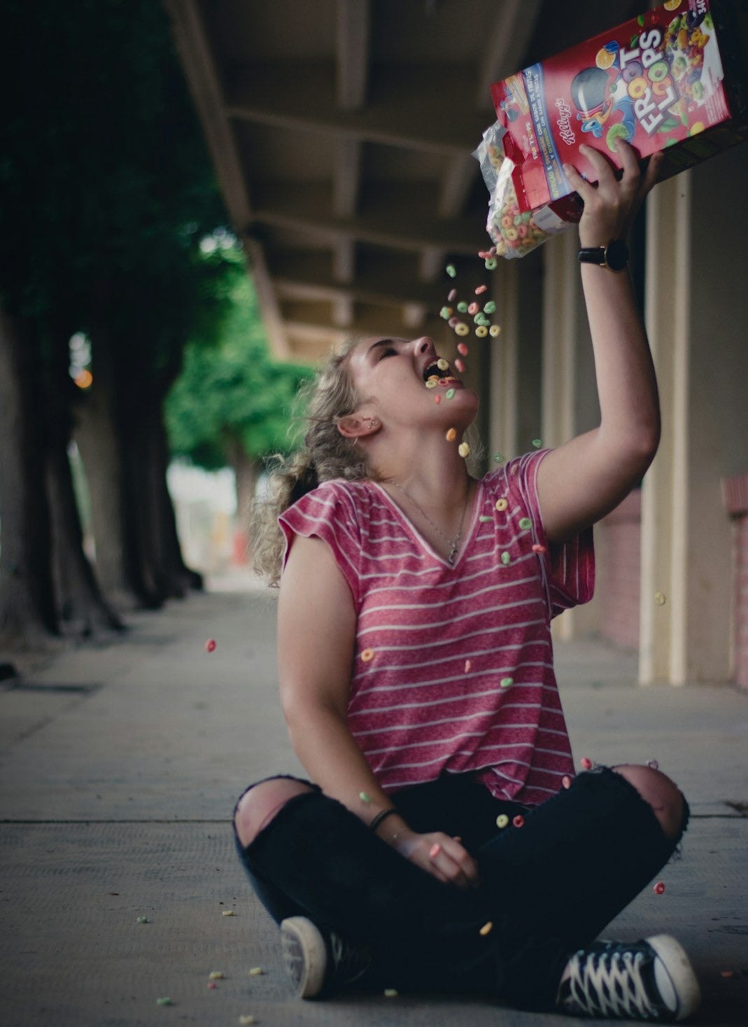 sitting woman holding Froot Loops cereal box above her head sitting woman holding Froot Loops cereal box above her head