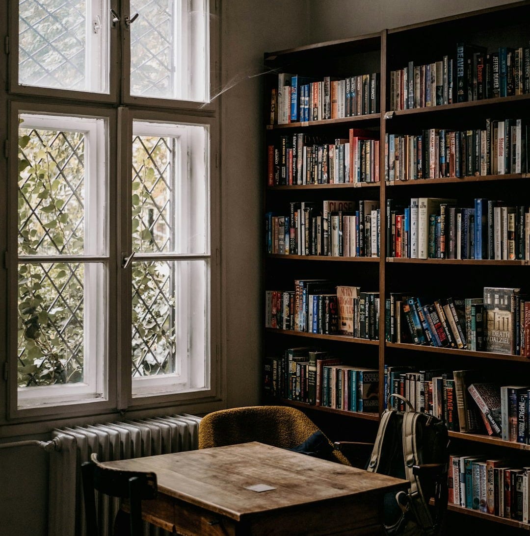 a wooden table sitting in front of a window filled with books a wooden table sitting in front of a window filled with books