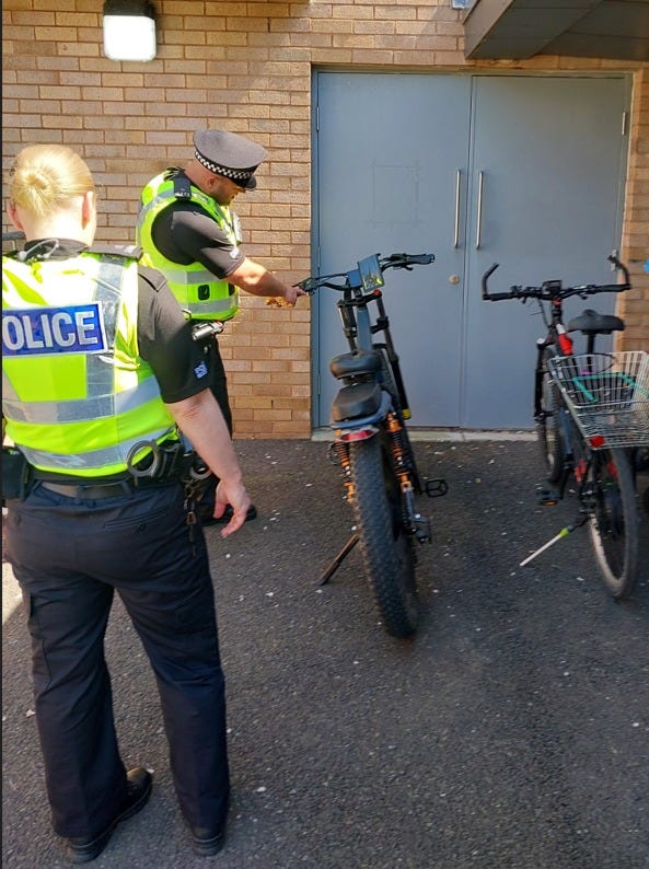 Two police officers are carrying out checks on two e-bikes which have been seized as part of a road safety day of action in Greater Glasgow Division.