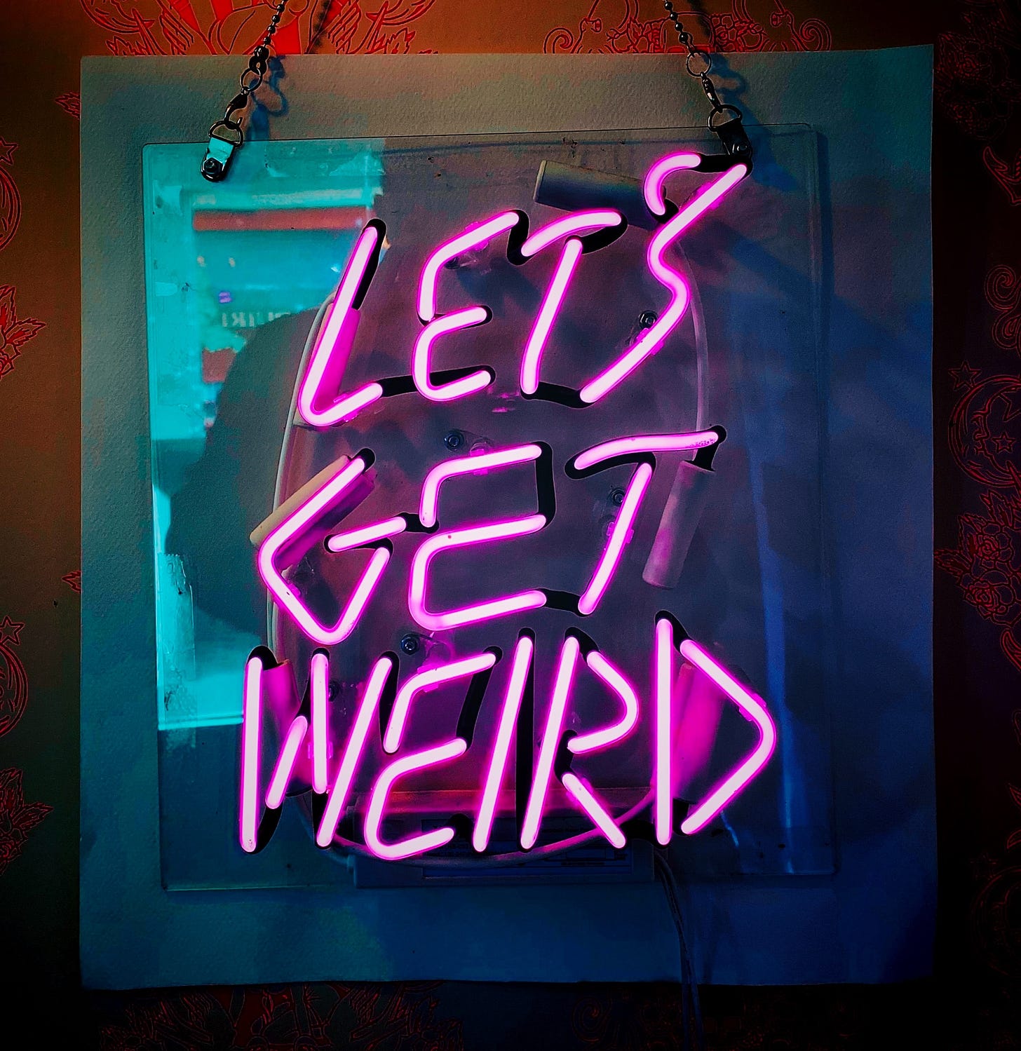 A pink neon sign that says "Let's get weird".