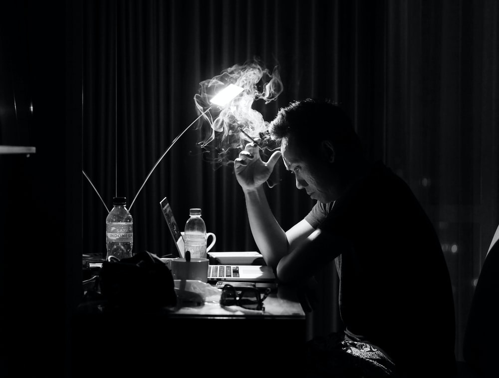 greyscale photography of man sitting on chair