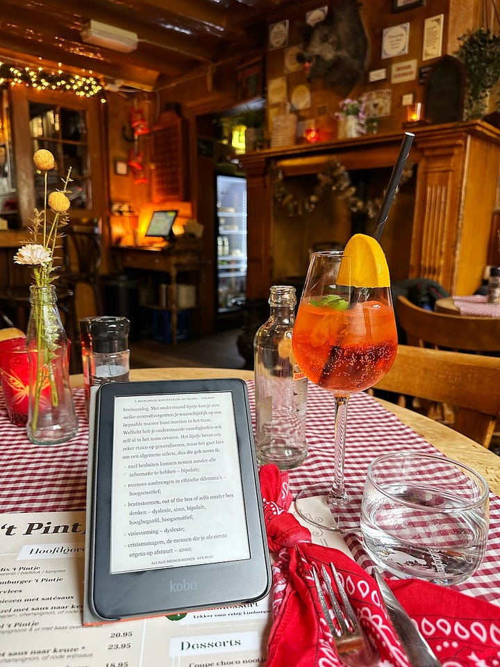Een kersenboom in bloei, een smal wandelpad tussen weilanden in de heuvels, een e-reader en een Apérol Spritz in een gezellig huiskamercafé, een glas cava op een terras onder blauwe regen.