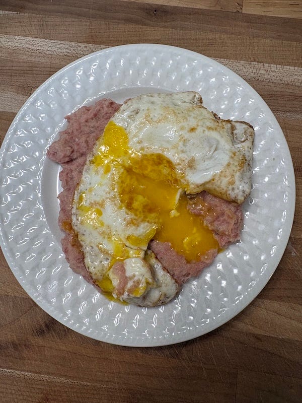 A small plate with corned beef, laden mashed potatoes, and a fried egg on top A small plate with corned beef, laden mashed potatoes, and a fried egg on top