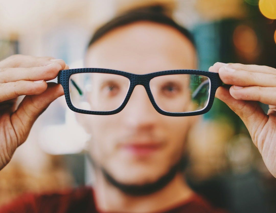 person holding eyeglasses with black frames person holding eyeglasses with black frames