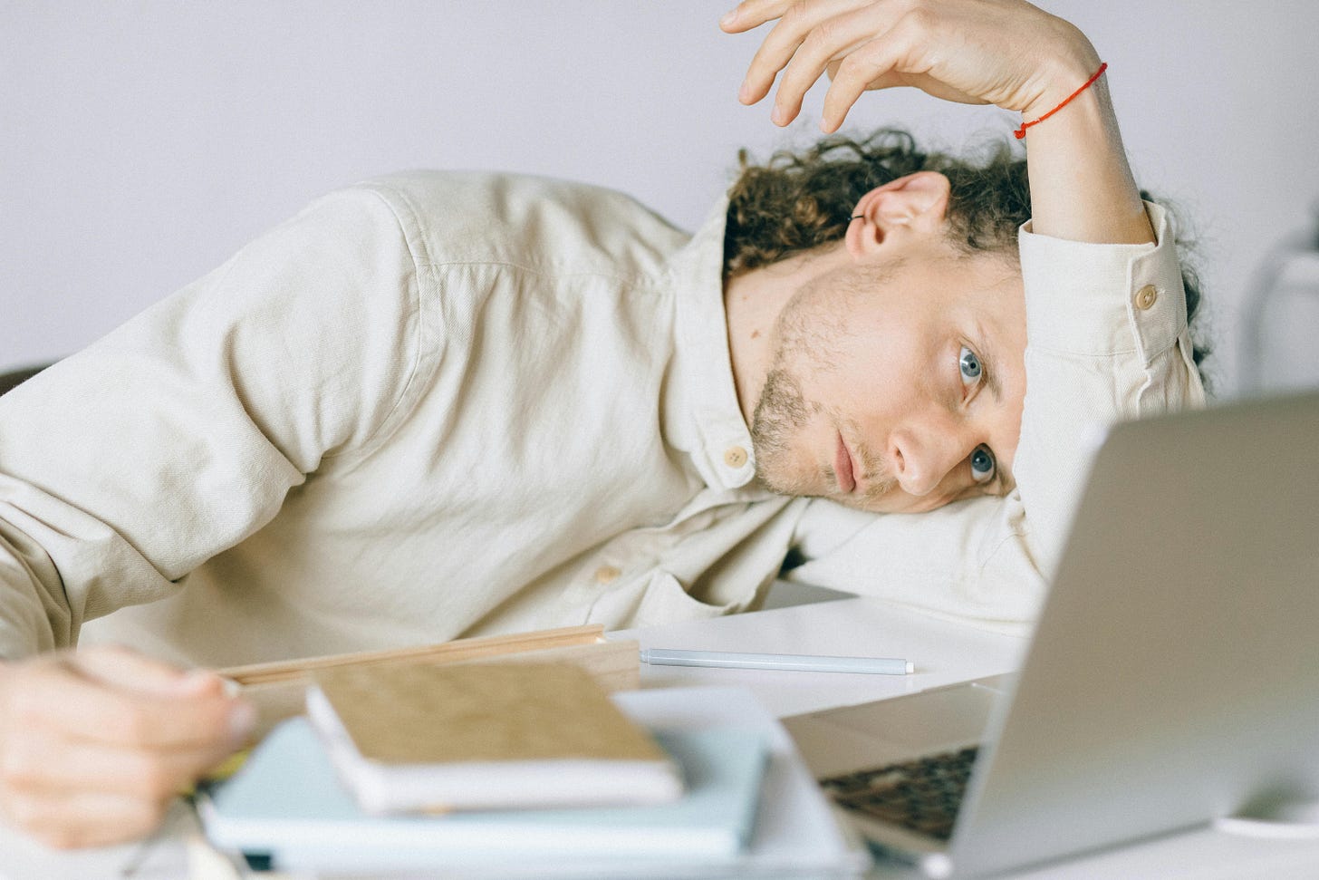 Free A tired Caucasian man at a desk, showing signs of exhaustion and stress, exemplifying workplace burnout. Stock Photo