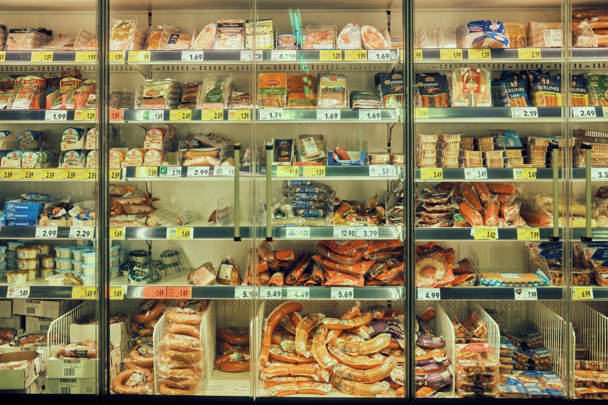 una nevera de un supermercado con un montón de alimentos envasados en plástico