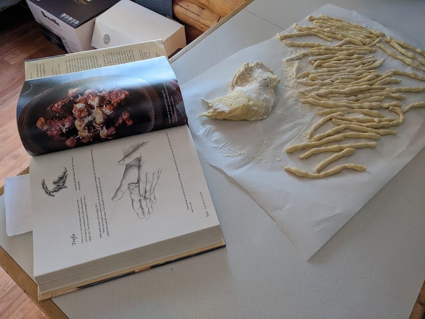 a photo of strips of pasta being broken off a large chunk of dough
