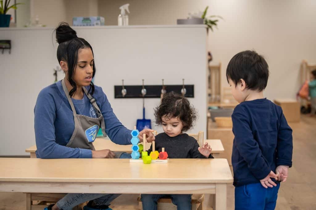 Young children exploring body autonomy with teacher at Montessori classroom.