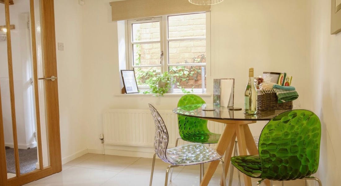 A room with white walls, a wooden door, and dining table with a hamper on it
