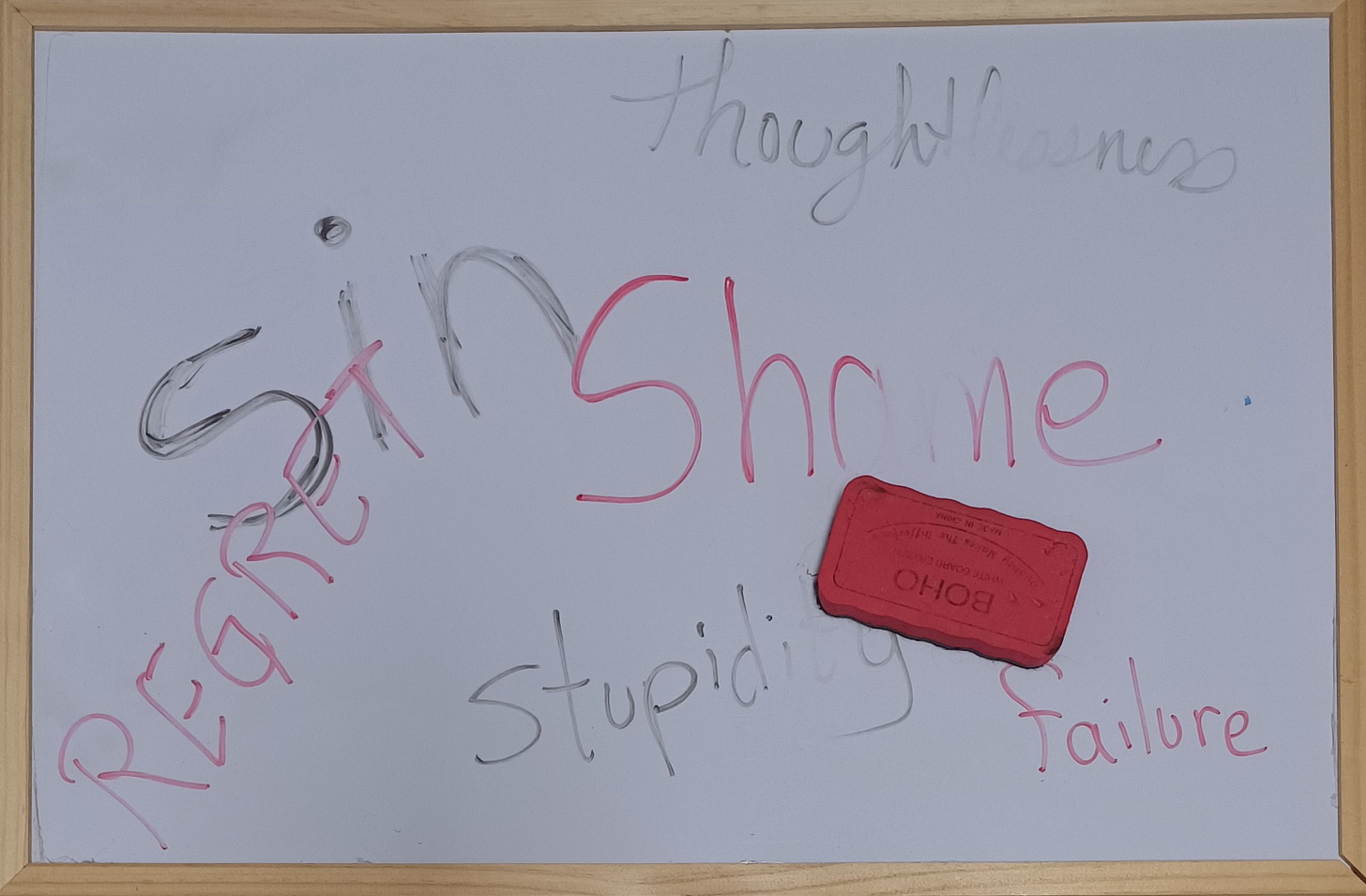 Whiteboard with words Sin, Stupidity, Thoughtlessness in black, Regret, Shame, Failure in red, partially erased with eraser Whiteboard with words Sin, Stupidity, Thoughtlessness in black, Regret, Shame, Failure in red, partially erased with eraser